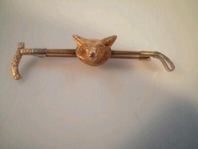 A fox mask and whip bar brooch marked for 9ct