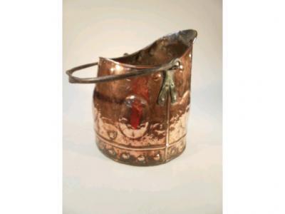 An antique copper coal scuttle with embossed and hammered decoration