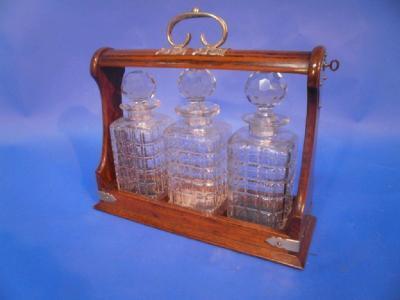An oak Tantalus with silver plated mounts and three square cut decanters