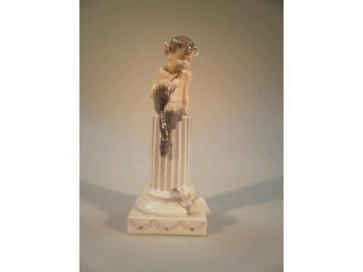 A Royal Copenhagen figure of a young faun seated on a fluted pillar looking at a mouse