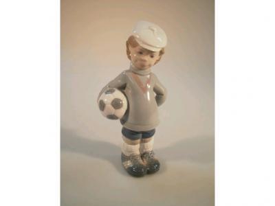 A Lladro figure of a young boy holding a football