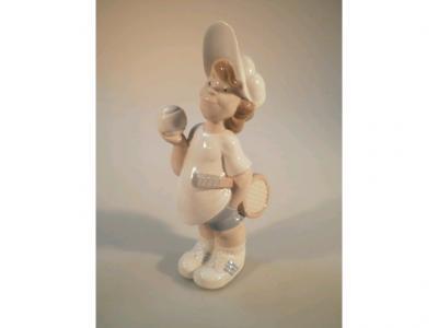 A Lladro figure of a young boy with a tennis racquet and ball