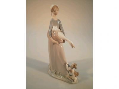 A Lladro figure of a young goose girl holding a goose in a basket with