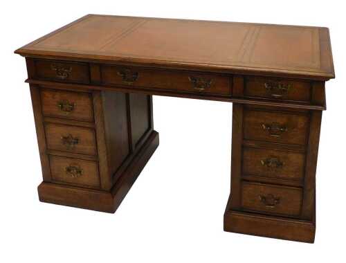 A late Victorian oak twin pedestal writing desk, with tooled leather top raised above three...