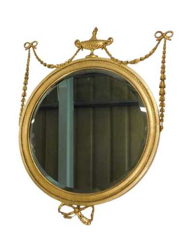 A Neoclassical Adam design wall mirror, the circular bevelled glass in beaded frame surmounted...