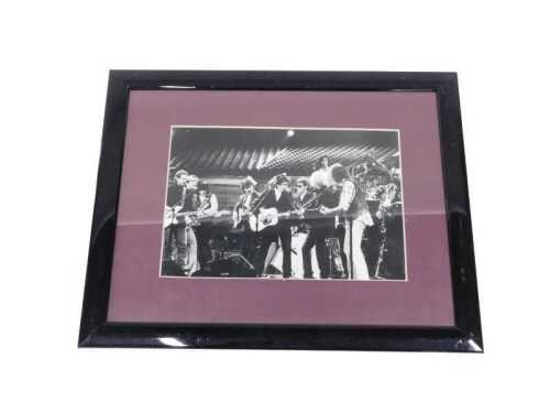 A black and white photographic print of The Travelling Wilburys on stage, mounted and framed,...