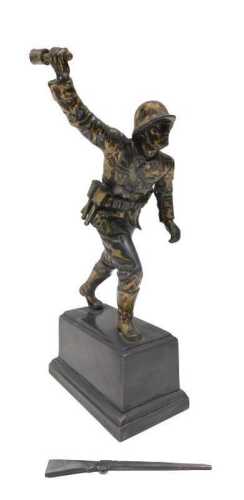 A 20thC cast metal figure of a German soldier, holding a stick grenade, loose rifle, on plinth...