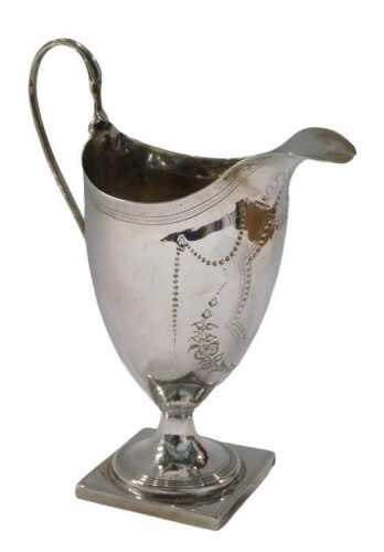 A George III silver helmet shaped cream jug, with strap work handle, inverted stem and square...