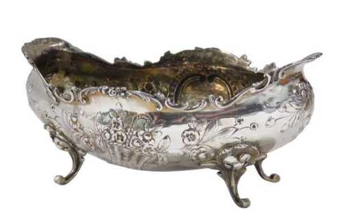 A 19thC boat shaped dish, repousse decorated with scrolls and flowers, on scroll feet, mark...