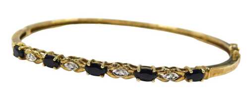 A sapphire and diamond half hinged bangle, set with five oval sapphires, claw set, with four...