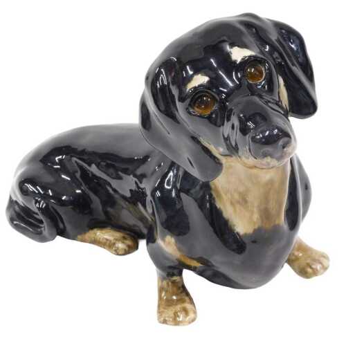 A 20thC Winstanley pottery fireside style figure of a seated Dachshund, marked beneath, 29cm high.