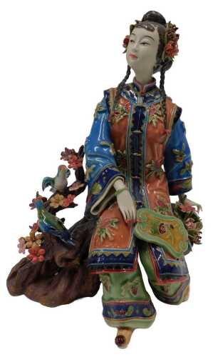 A 20thC Japanese Taisho style figure of a geisha, on a naturalistic setting beside birds and...