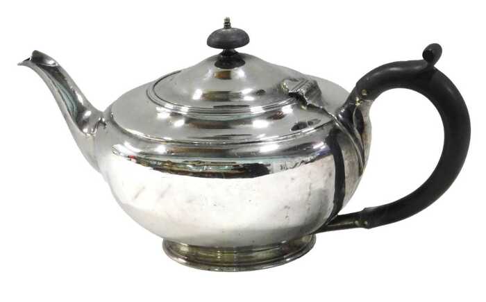 A George V silver teapot, by the Harrison Brothers, of circular form, with ebonised thumb mould...