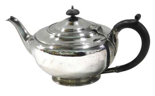 A George V silver teapot, by the Harrison Brothers, of circular form, with ebonised thumb mould...
