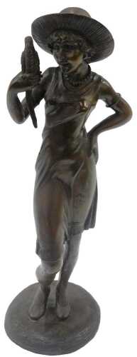 A 20thC bronze figure of lady in hat holding bird, on circular base, 57cm high.