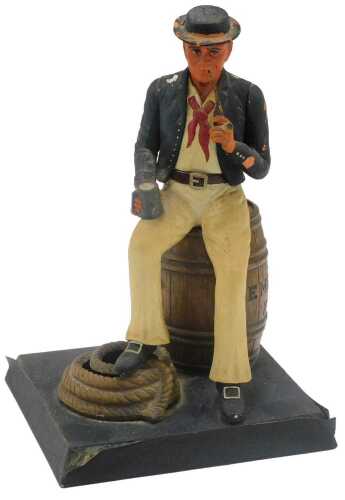 A 20thC figure group of a seated sailor on demerara rum barrel, in colours, 20cm high.