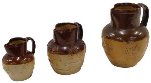 A graduated set of late 19thC Doulton two coloured stoneware jugs, each with strap handles,...