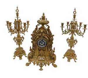 A 20thC gilt metal clock garniture, the 9cm diameter raised enamel Roman numeric dial housed in...