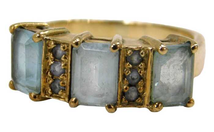 A 9ct gold dress ring, set with rectangular cut aquamarines and six round brilliant cut pale...