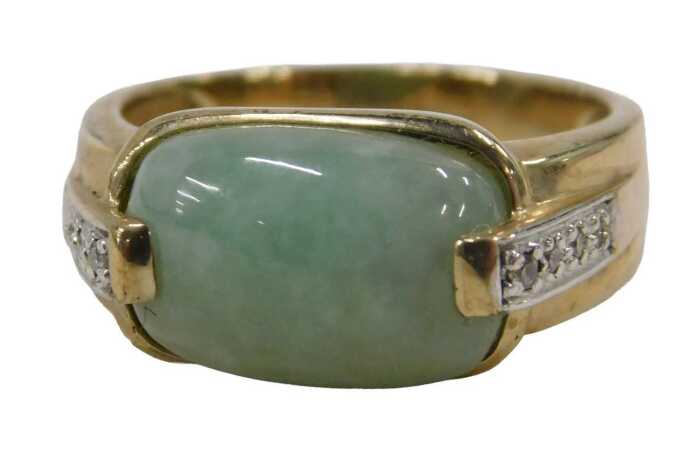 A 9ct gold jade and diamond dress ring, the oblong pale jade, with four tiny diamond set...