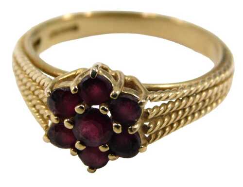 A 9ct gold garnet cluster ring, set with seven round brilliant cut garnets, on four splayed rope...
