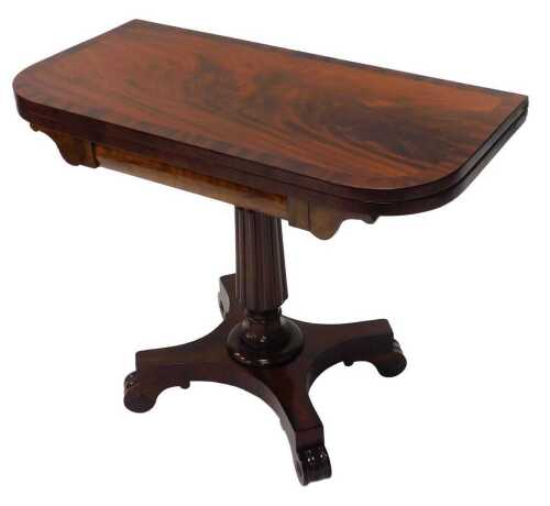 An early 19thC mahogany fold over card table, the top with wide cross banding raised on a reeded...