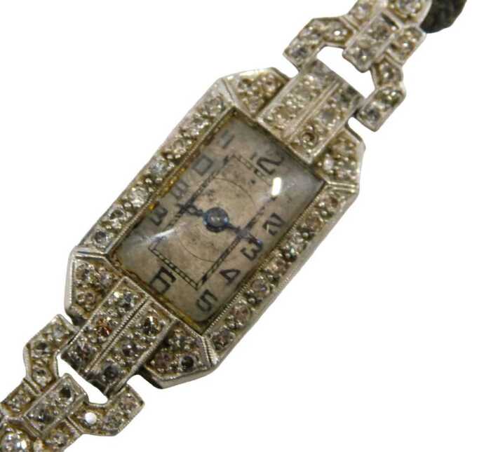 An Art Deco lady's cocktail watch, the case set with tiny diamonds, the dial with blue hands and...