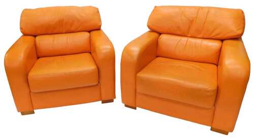 Two deep seated armchairs, in tangerine leather, 100cm wide.