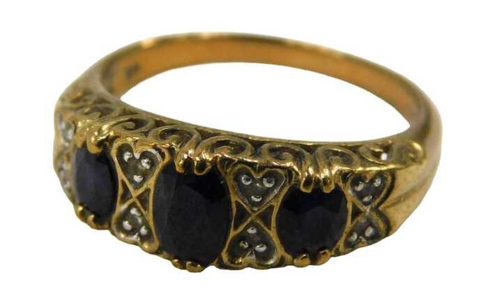 A 9ct gold garnet and diamond half hoop dress ring, set with three oval cut garnets each claw...