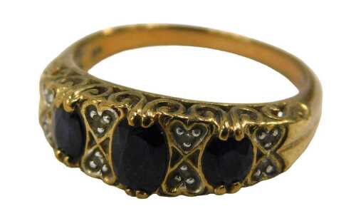 A 9ct gold garnet and diamond half hoop dress ring, set with three oval cut garnets each claw...
