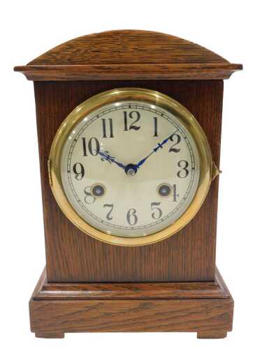 An Edwardian oak cased mantel clock, the 11cm diameter Arabic dial in a domed case, on...