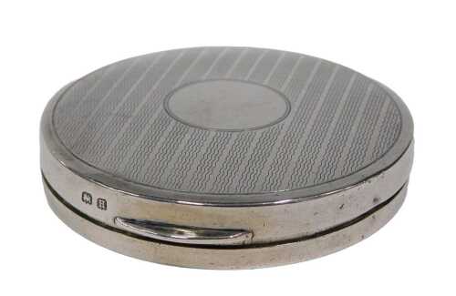 A George V silver powder compact, of circular form, the hinged lid partially engine turned with...