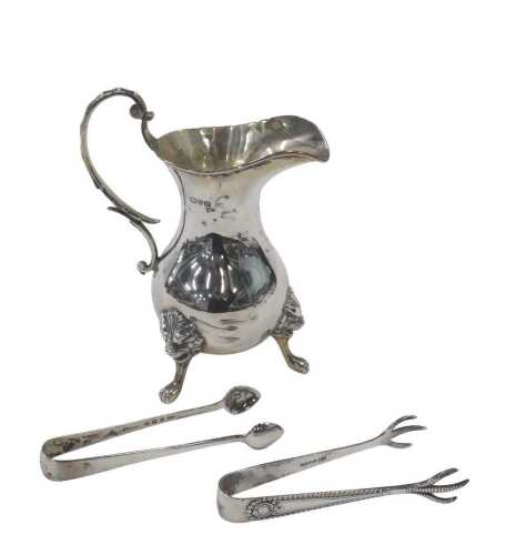 A George V silver cream jug, with S scroll handle, bulbous body, triple lion mask capped paw...