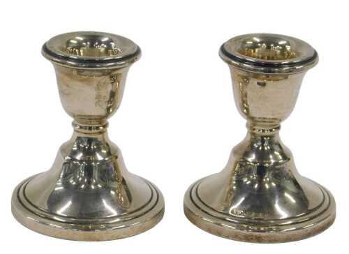 A pair of George V silver dwarf candlesticks, each with urn dish holders on inverted stems and...