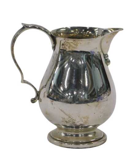 A George VI silver cream jug, with beak spout, thumb mould ear handle, plain bulbous body and...