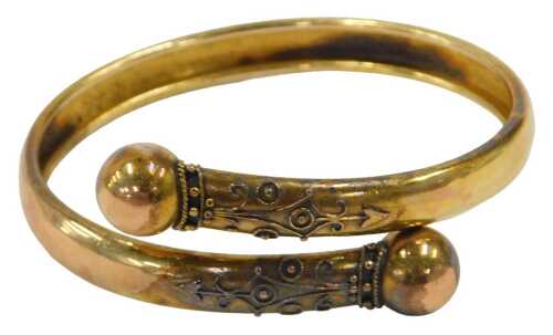 An early 20thC torque bangle, the two splayed bracelet, with raised ball and scroll design, and...
