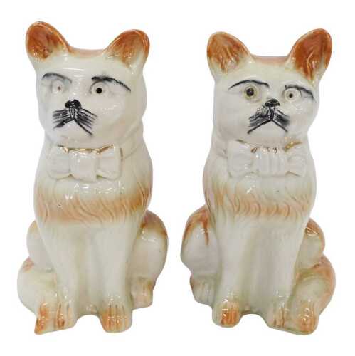 A pair of early 20thC pottery freestanding cats, each press moulded picked out in brown with...
