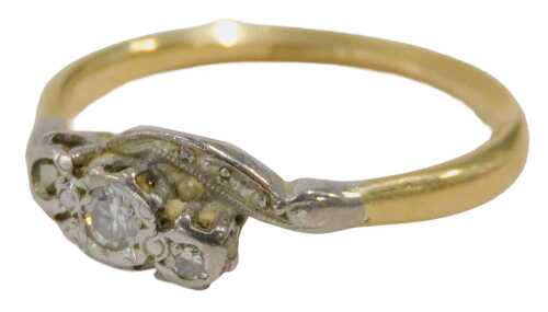 A diamond twist ring, the central three stone set section in platinum, on a yellow metal band,...