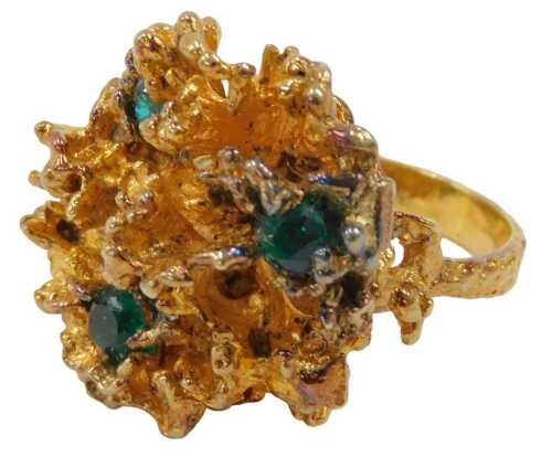 An abstract dress ring, the waved design ring head set with three emeralds, in a brushed and...