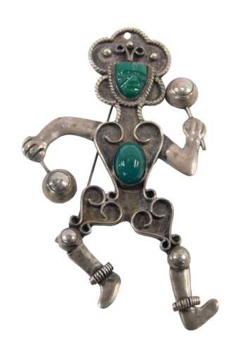 A malachite brooch, formed as a figure playing maracas, in the Mexican style, white metal...
