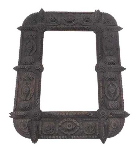 A heavily carved Tramp Art mirror, the border profusely carved and raised with oval medallions...