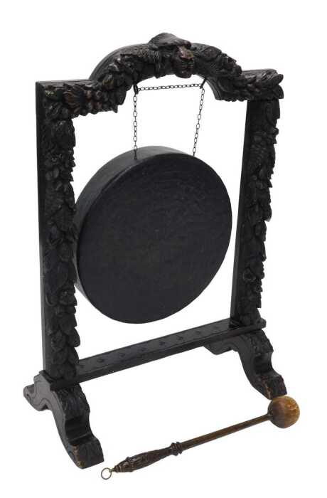 A 19thC oak framed dinner gong, heavily carved with lion's masks surrounded by berries, leaves...