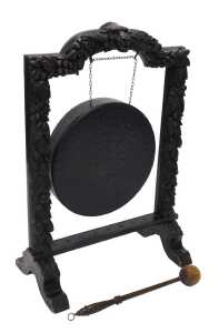 A 19thC oak framed dinner gong, heavily carved with lion's masks surrounded by berries, leaves...