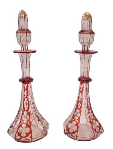 A pair of 19thC Bohemian ruby glass decanters, each with shaped stoppers on cylindrical stems...