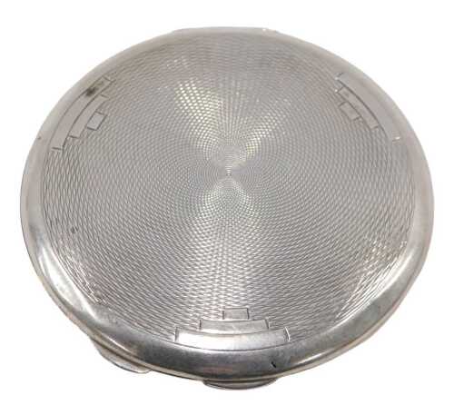 A George V silver powder compact, of circular form, with thumb mould handle, engine turned back,...
