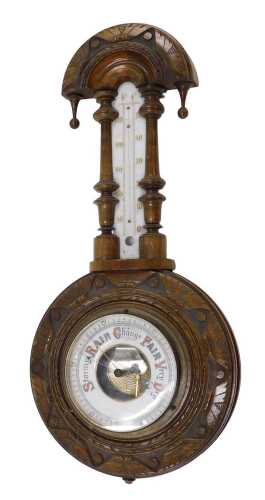 An early 20thC walnut cased wheel barometer and thermometer, in a heavily carved walnut case,...