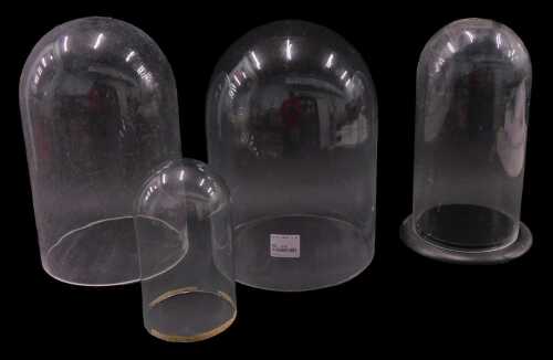 A glass dome, 39cm high, 22cm diameter, and others of varying sizes, one on an ebonised base. (4)