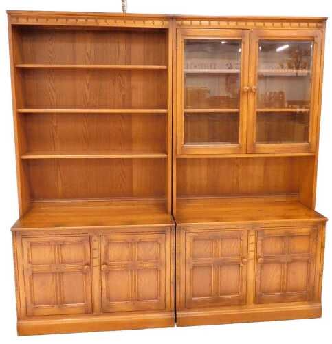 Two similar Ercol bookcases, the first with open shelves above a double cupboard, the second...