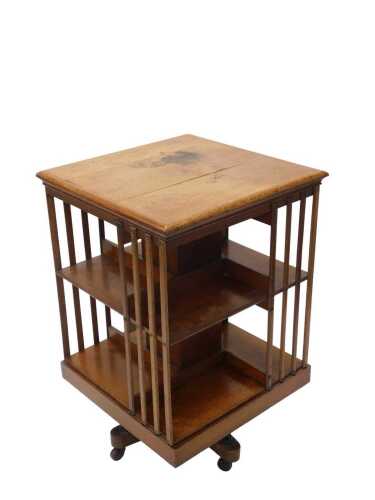 An Edwardian oak revolving bookcase, of square form, on a platform base with articulated section...