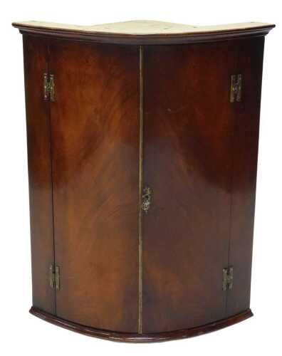 An early 19thC mahogany barrel corner cupboard, the flame veneered doors revealing a fitted...